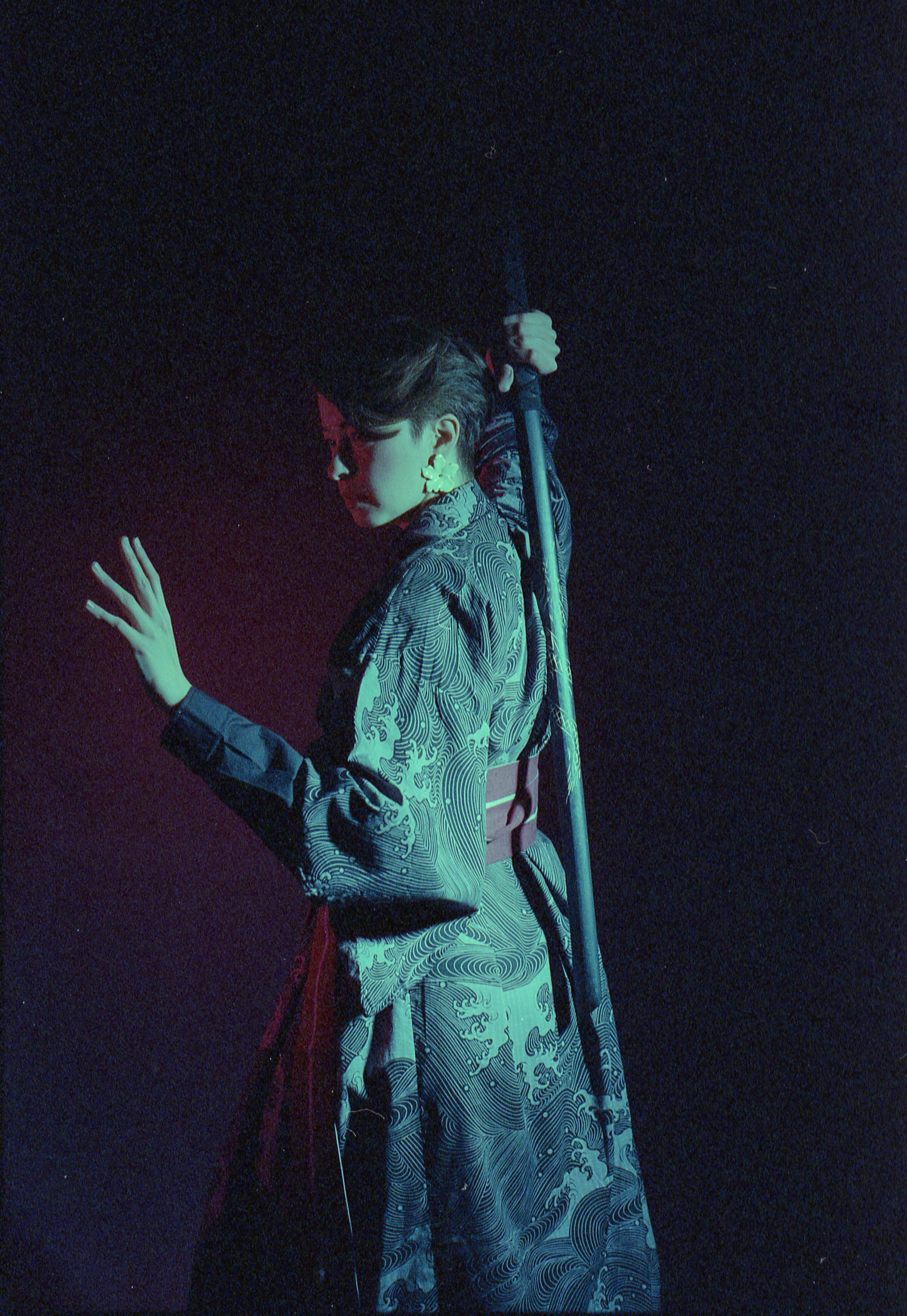 Yulia turning away in green light, hand outstretched